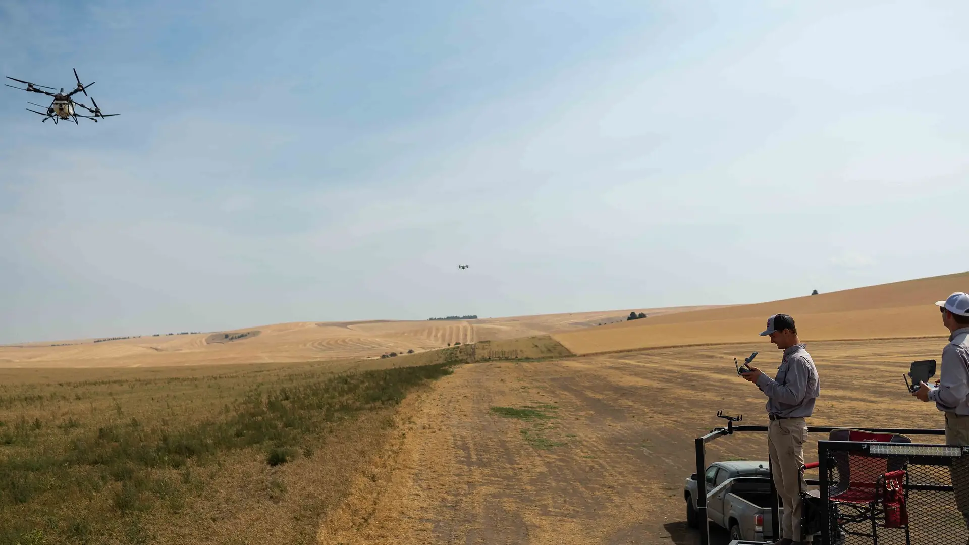 RADS operators on the platform trailer in harvested wheat country with a drone overhead